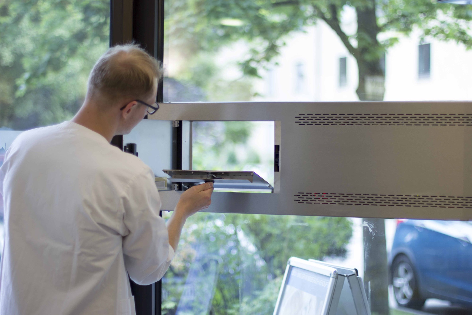 Eine DACOS Notdienstanlage mit komfortabler Durchreiche, Abbildung von der Apothekenseite in kundenfreundlicher Arbeitshöhe direkt in das Apothekenschaufenster eingesetzt.