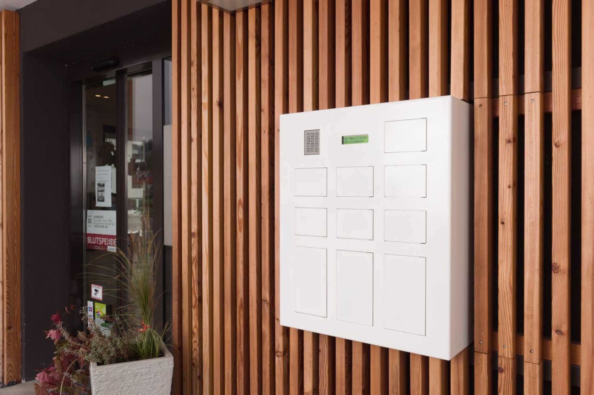 Eine DACOS Abholfachanlage mit 10 Fächern im Fenster integriert. Ermöglicht die Abholung von Medikamenten auch außerhalb der Öffnungszeiten von Apotheken. Bester Kundenservice 24/7 – DACOS findet immer die die beste und induviduelle Lösung für Ihre Fassade.