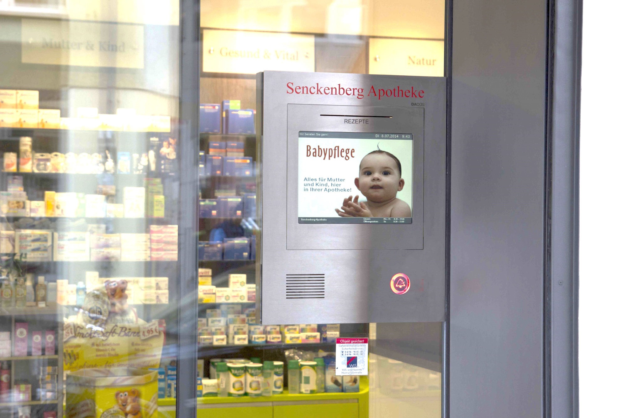 Der rote Klingelknopf weist dem Kunden den Weg zur praktische DACOS Notdienstanlage, hier mit Bildschirm für die Notdienstanzeige und Werbung. Die bequeme Arbeitshöhe der Durchreiche erleichtern den Kundenservice erheblich. Stabile und wartungsarme Ausführung von Marktführer DACOS.